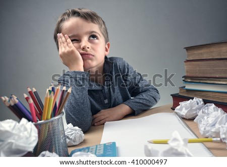 Thinking child bored, frustrated and fed up doing his homework