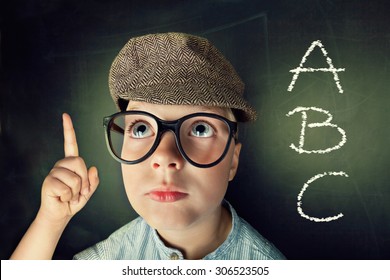 Thinking Child With Thick Eyeglasses At A Blackboard In The Background 