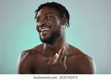 Thinking, cologne and blue background with a model black man posing shirtless in studio for body spray. Perfume, product or skin with a handsome, muscular and young male standing topless on space