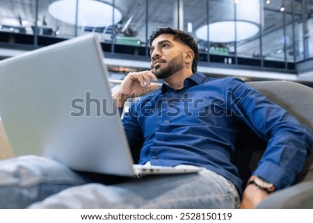 Thinking deeply, man working on laptop in modern office environment. Business, professional, technology, brainstorming, concentration, productivity