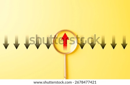Thinking differently and finding new perspectives. Magnifying glass focuses on a red upward arrow among black downward arrows, innovation, leadership, breakthrough, unique thinking, problem-solving