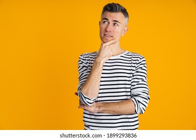 Thinking handsome man posing and looking aside isolated over yellow background
