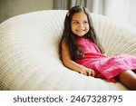 Thinking, home and child on chair with smile for comedy joke, growth and creative inspiration for prank. Seat, thoughts and young girl in house with future ideas for imaginary friend and comic meme