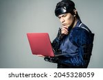 Thinking Japanese armed samurai who uses a laptop PC.