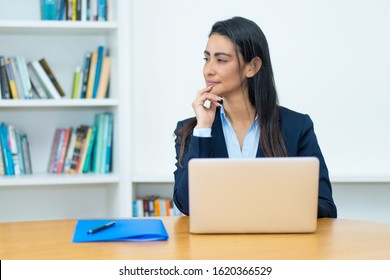 Thinking Latin American Mature Businesswoman With Blazer At Computer At Office