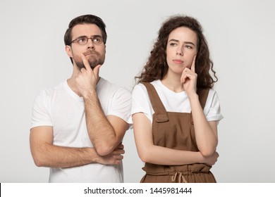 Thinking millennial couple pose isolated on grey studio background, pretty girl handsome guy wearing glasses touch chin posture of indecision doubting feelings anxiety, deliberating brain work concept - Shutterstock ID 1445981444