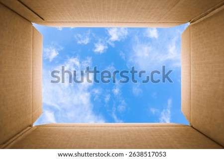 Thinking outside the box concept: Blu sky with some white clouds viewed from inside of a cardboard box. The carton sides are aligned with the image sides and sky is framed in the center of the image.