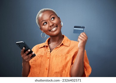 Thinking, phone and credit card with a black woman online shopping in studio on a gray background. Mobile, ecommerce and finance payment with a young female shopper searching for a deal or sale - Powered by Shutterstock