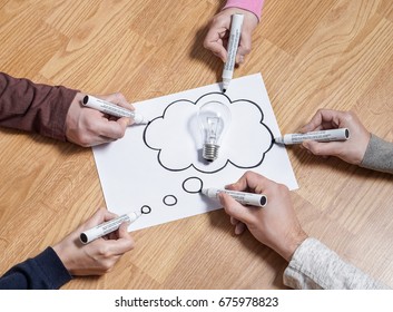 Thinking speech bubble balloon with light bulb. Brainstorming new ideas together for marketing plan or school project. Teamwork, synergy and education. Group of people drawing to same paper.