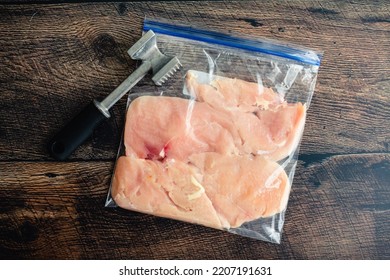 Thinly Pounded Chicken Breast Cutlets in a Plastic Bag: Overhead view of thinly pounded chicken cutlets with a meat mallet