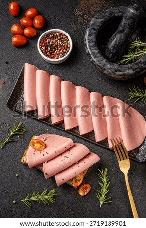 Thinly sliced ham served with bread tomatoes herbs and spices in a dark rustic setting creating a premium deli food scene for restaurant menu and commercial use