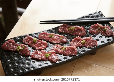 Thinly sliced raw beef, known as Yuk-sa-si-mi, elegantly plated with fresh garnishes.