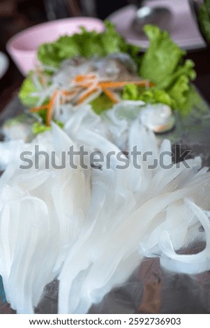 Thinly sliced raw squid sashimi served on a plate with fresh vegetables, highlighting its translucent texture and delicate presentation.