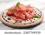 thinly sliced salami. delicious snack rustic salami on wooden white background
