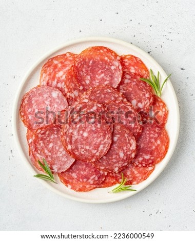 Thinly sliced salami sausage on a plate, top view