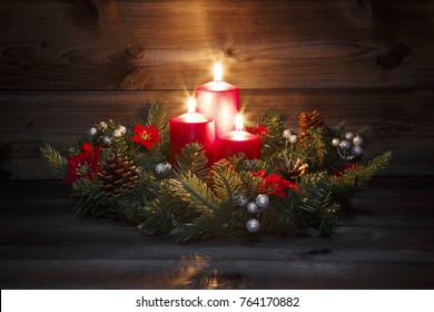 Third Advent - Decorated Advent wreath with three red burning candles on a wooden background with festive atmosphere
