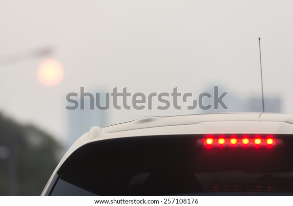 Third brake\
lights of white car in foggy\
evening