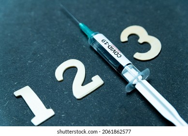 Third covid vaccine dose and jab concept with numbers. Syringe is seen on table as a concept for the 3rd covid-19 vaccine dose, also called booster shot - Shutterstock ID 2061862577