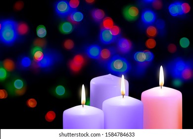 Third Gaudete Sunday of the Advent. Christmas violet, purple and pink candles. Xmas concept on a bokeh background. Shepherd Joy Candle.