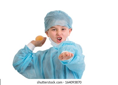 Third Grade Mischievous Elementary Kid Looking At You And Throws His Bouncy Egg Project To See If Really Bounces, He Is Wearing Blue Scrubs