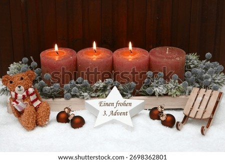 Third Sunday of Advent: Rust-colored Advent candles decorated with a teddy bear, Christmas baubles, and a sled in the snow. A star bears the inscription 