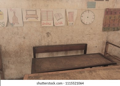 Third World Education - Inside Of A Poor African School Classroom, With Dirty Walls, Old School Dusty Wooden And Metal Benches, And Colorful Drawings, In The Gambia, Africa