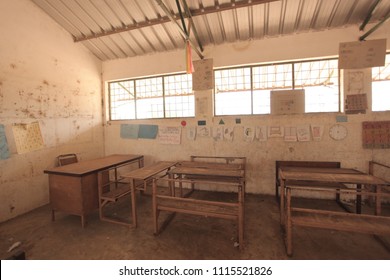 third world education - inside of a poor african school classroom, with dirty walls, old school dusty wooden and metal benches, and colorful drawings with bright window , in the Gambia, Africa