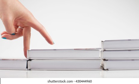 The Thirst For Knowledge. Self. A Staircase Made Of Books. The Hand Is Symbolizing The Man Climbs Up The Stairs Of Books On White Background