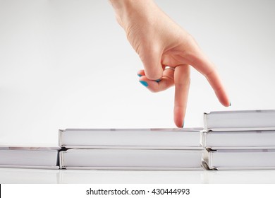 The Thirst For Knowledge. Self. A Staircase Made Of Books. The Hand Is Symbolizing The Man Climbs Up The Stairs Of Books On White Background