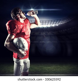 Thirsty American football player in red jersey drinking water against american football arena - Powered by Shutterstock