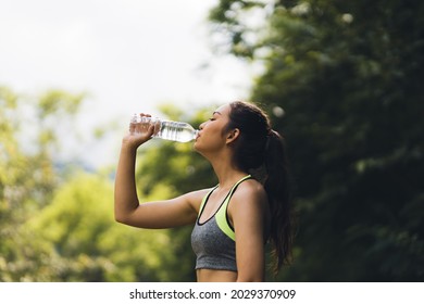 A thirsty Asian female athlete is drinking water after a workout. - Powered by Shutterstock