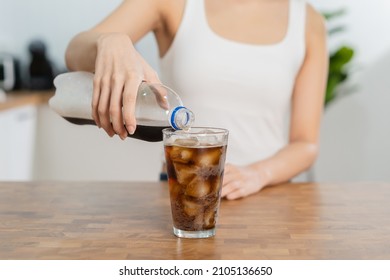 Thirsty, Asian Young Woman, Girl Holding,  Pouring Cold Cola Soft Drink Soda, Sparkling Water With Ice Sweet Sugar From Bottle Into Glass In Her Hand. Health Care, Healthy Diet Lifestyle Concept.