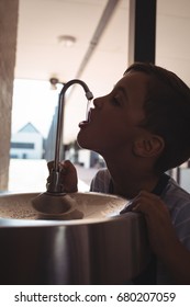 Thirsty Boy Drinking Water From Faucet At School