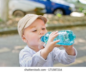 Thirsty Child Drinking From A Plastic Bottle And Spilling The Water