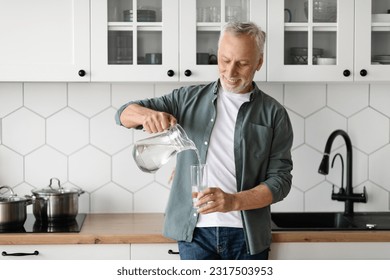 Thirsty Senior Man Pouring Water From Jug To Glass In Kitchen Interior, Portrait Of Happy Smiling Elderly Gentleman Drinking Healthy Liquid At Home, Enjoying Refreshing Drink, Copy Space - Powered by Shutterstock