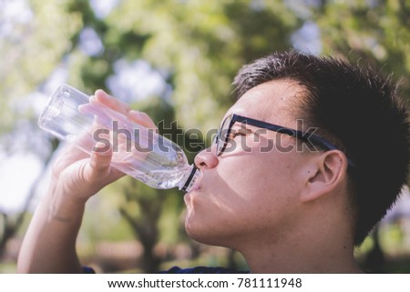 a thirsty tired man drinking water from the bottle until it empty after exercise activity running in the park