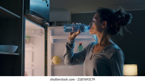 Thirsty Woman Standing In Front Of The Fridge And Drinking Water Late At Night