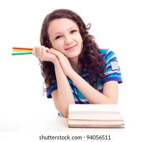 Thirteen Year Old Schoolgirl Sitting By The Table With Pens And Books, Isolated Against White Background