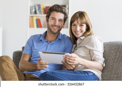 Thirty Year Old Couple On App Tablet Pc In Modern White Home.