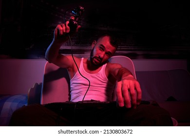 A Thirty-year-old Guy With A Joystick In His Hands Is Playing Computer Games, Experiencing Anger, Indignation. Sitting On The Couch At Home. View From The TV Side.