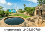 Thirumoorthi stone carved cave with ancient round well with town in the background, Mahabalipuram, Tondaimandalam region, Tamil Nadu, South India
