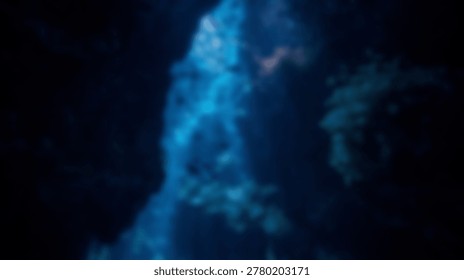 This abstract blurred image features dark blue and cyan light patterns, creating a mysterious and deep atmospheric background texture, reminiscent of an underwater cave or deep sea environment.
