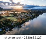 This aerial photograph captures the tranquil beauty of Mission, BC, Canada at sunrise, showcasing misty landscapes, serene river reflections, and lush greenery.