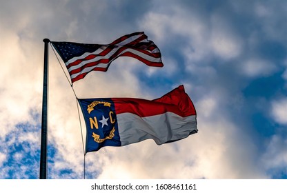 This is the America and North Carolina flag flying beautifully on a dark cloudy day.
