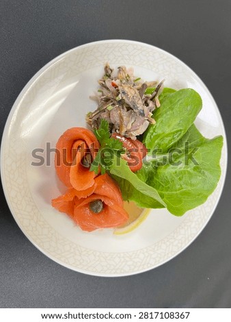 This appears to be a cold smoked salmon appetizer salad plated in a finedining or airline catering style.