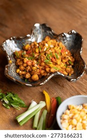 This appetizing image features a wholesome bowl of corn chaat, brimming with fresh corn kernels and colorful vegetables, set against a rustic wooden backdrop.
