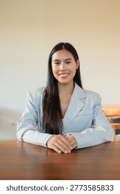 This authentic vertical portrait captures a beautiful young Thai woman from the Isan region looking directly at the camera with a joyful, toothy smile. This genuine and honest representation of a modern Southeast Asian professional showcases a stunning female in a moment of happy, confident engagement. Dressed in a stunning light grey linen blazer with a visible natural texture, she sits at a minimalist wooden table within a bright, airy cafe interior. The stunning subject is captured in a classic headshot style, her cheerful expression and direct eye contact reflecting a real, unretouched human connection. This high-quality lifestyle photograph emphasizes an unaltered aesthetic, ideal for commercial projects seeking authentic representation of professional life, positive work culture, and approachable leadership. The background is a clean, contemporary space featuring a minimalist wall and warm, natural daylight that highlights her genuine features and smooth dark hair. This genuine moment reflects the rising demand for diverse representation in the global workforce, blending elegance with a relaxed, urban atmosphere. The vertical composition is expertly balanced, offering significant negative space and copy space above her for editorial headlines or advertising overlays. Every detail, from the subtle weave of the linen fabric to her friendly, approachable gaze, is rendered with professional clarity. This real-life scenario is perfect for marketing campaigns focused on entrepreneurship, university student life, or modern corporate recruitment. The honest happiness and unretouched skin texture provide a relatable feel that converts exceptionally well in today's visual market. As example of an Esan female, this image serves as a powerful asset for global brands prioritizing inclusion and authentic storytelling. Every pixel of this scene, from the minimalist room to the genuine smile, is designed to resonate with humans searching for honest, high-intent visual content.