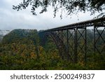 This is an autumn moody view of the New River Gorge Bridge, a steel Corten arch along US Route 19 and Corridor L, within the New River Gorge National Park and Preserve in West Virginia.