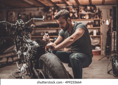 This Bike Will Be Perfect. Confident Young Man Repairing Motorcycle In Repair Shop