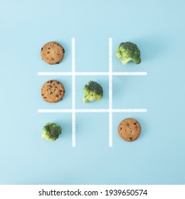 In this board game broccoli beats chocolate chip cookies, that means healthy food is better than junk food, so win this game. Creative flat lay concept.